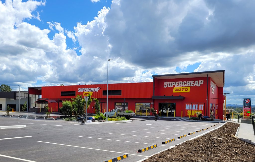 Industrial Buildings, Warehouse, retail buildings, Front on Exterior Image of Supercheap Auto, Red & yellow colours & Carpark displayed.