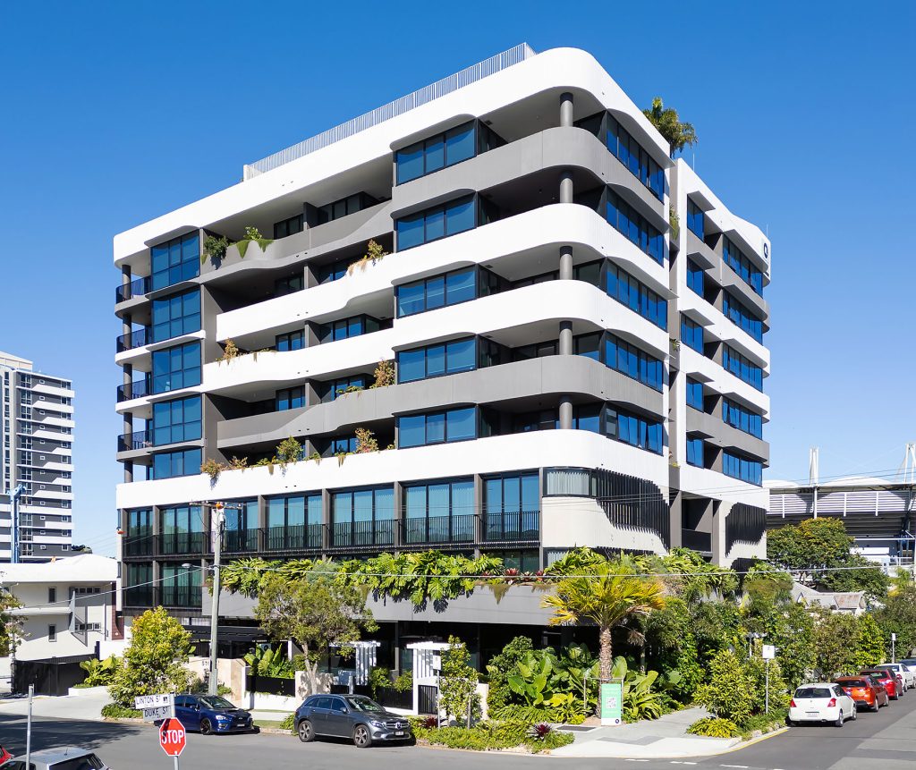 Exterior, multi-residential building, 8 storeys, white and grey building, trees and scrubs at the bottom.