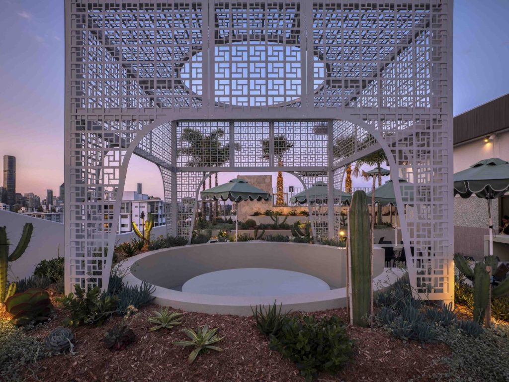 This image is taken on the roof of story house, it displays the garden bed, outdoor curved seating and green umbrellas.