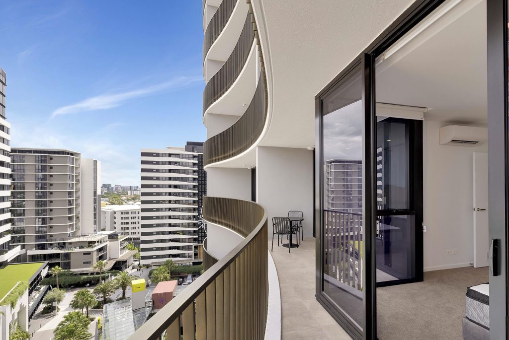 This image displays the curved facade of the building, as well as the bedroom's view of South City Square.